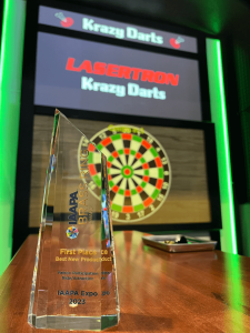 Krazy Darts Wins 2023 IAAPA Brass Ring for Best New Product - Award sits on table in front of darts game